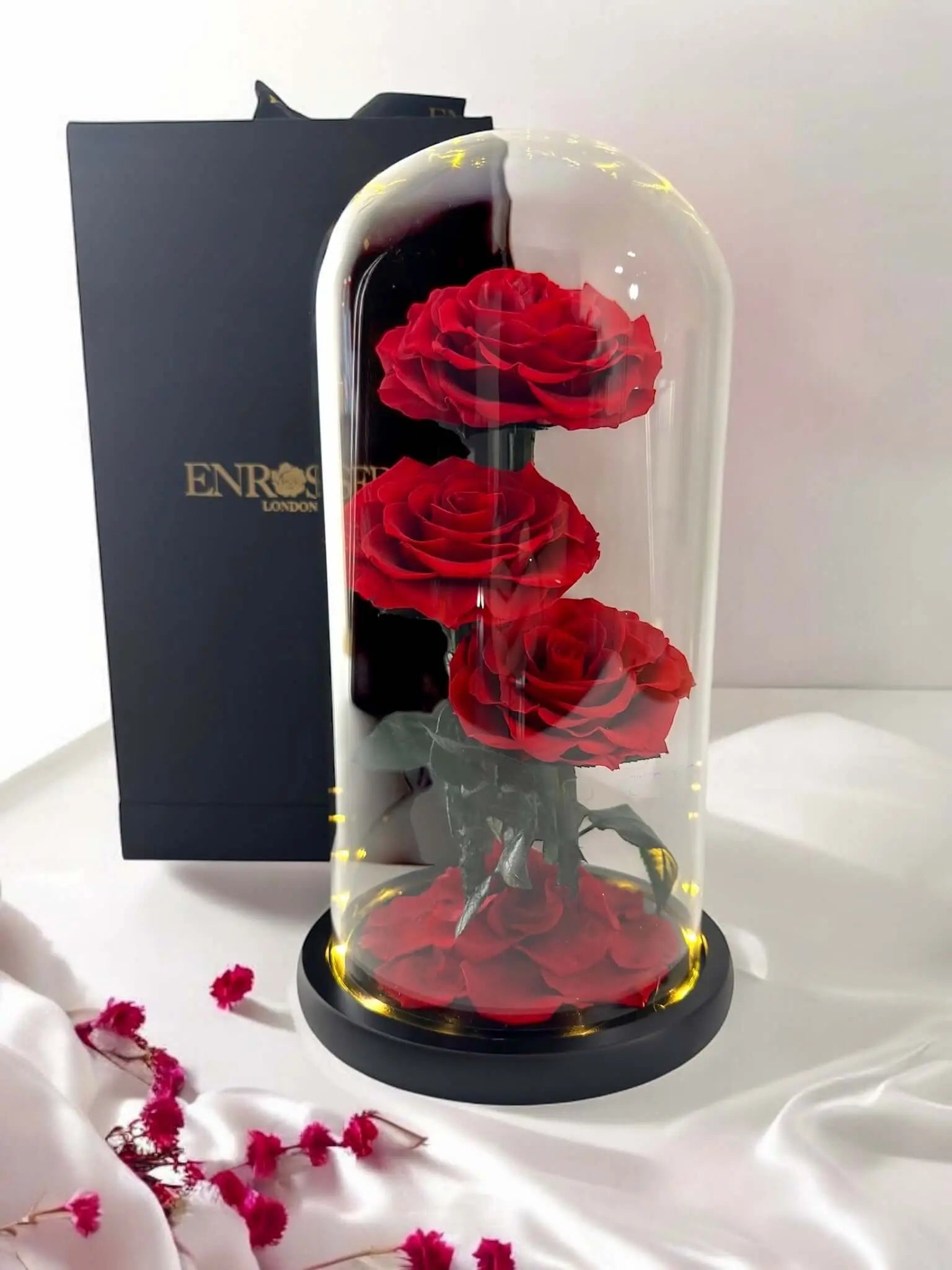 Triple Elegance Grandi with three red roses under a glass dome and LED lights in an elegant gift box.